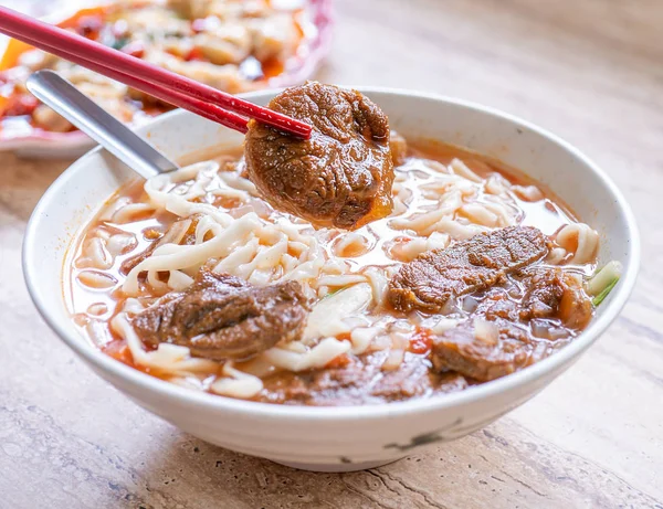 Beef noodle - Taiwan ramen meal with tomato sauce broth in bowl on bright wooden table, famous chinese style food, close up, top view, copy space
