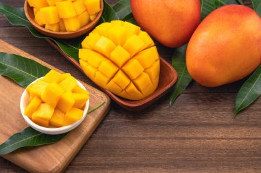 Ahşap kesme tahtası ve rustik ahşap arka plan taze doğranmış mango küpleri. Tropikal yaz meyve konsepti, yakın çekim, makro, kopyalama alanı.