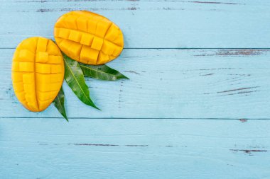 Taze mango - parlak mavi ahşap arka plan üzerinde yeşil yaprakları ile güzel doğranmış meyve. Tropikal meyve tasarım konsepti. Düz yatıyordu. Üst te. Kopyalama alanı
