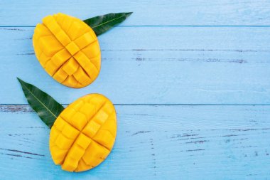 Taze mango - parlak mavi ahşap arka plan üzerinde yeşil yaprakları ile güzel doğranmış meyve. Tropikal meyve tasarım konsepti. Düz yatıyordu. Üst te. Kopyalama alanı