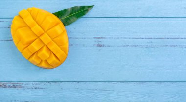 Taze mango - parlak mavi ahşap arka plan üzerinde yeşil yaprakları ile güzel doğranmış meyve. Tropikal meyve tasarım konsepti. Düz yatıyordu. Üst te. Kopyalama alanı