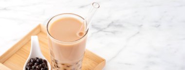 Tapioca inci topu kabarcık süt çayı, popüler Tayvan içecek, mermer beyaz masa ve ahşap tepsi üzerinde saman ile içme camı, yakın çekim, kopya alanı.