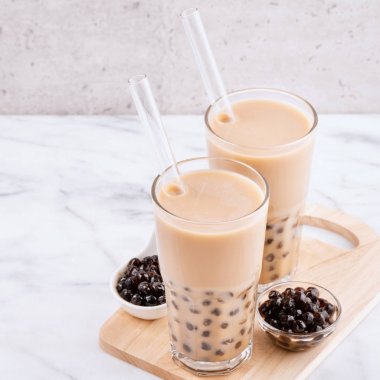Tapioca inci topu kabarcık süt çayı, popüler Tayvan içecek, mermer beyaz masa ve ahşap tepsi üzerinde saman ile içme camı, yakın çekim, kopya alanı.