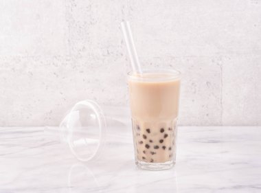 Tapioca inci topu kabarcık süt çayı, popüler Tayvan içecek, mermer beyaz masa ve ahşap tepsi üzerinde saman ile içme camı, yakın çekim, kopya alanı.