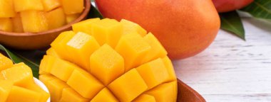 Bir tepsi ve parlak rustik ahşap arka planda taze doğranmış mango. Tropikal yaz meyve tasarım kavramı, yakın çekim, makro, kopya alanı.