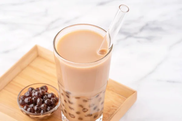 Tapioca pearl ball bubble milk tea, popular Taiwan drink, in drinking glass with straw on marble white table and wooden tray, close up, copy space. — Stock Photo, Image