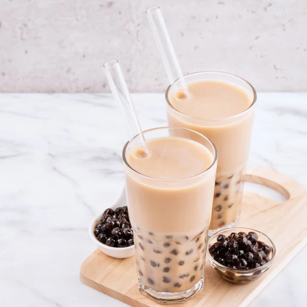 Tapioca bola de perla burbuja té de leche, bebida popular de Taiwán, en vaso de beber con paja en la mesa blanca de mármol y bandeja de madera, de cerca, espacio para copiar . —  Fotos de Stock