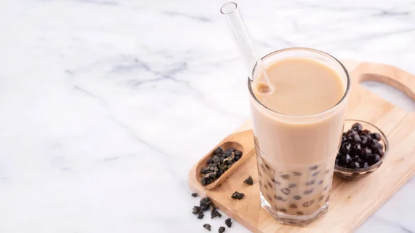 Tapioca bola de perla burbuja té de leche, bebida popular de Taiwán, en vaso de beber con paja en la mesa blanca de mármol y bandeja de madera, de cerca, espacio para copiar . — Foto de Stock