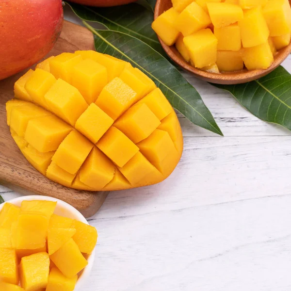 Färsk hackad Mango på en bricka och ljusa rustika trä bakgrund. Tropiska sommaren frukt designkoncept, närbild, makro, kopiera utrymme. — Stockfoto