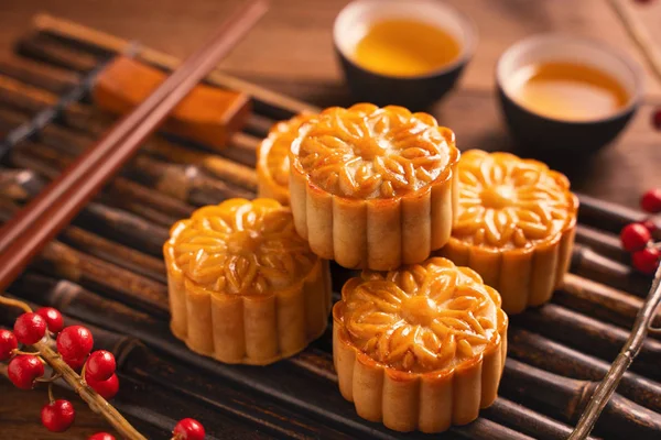 Moon cake Mooncake table setting - Chinese traditional pastry with tea cups on wooden background, Mid-Autumn Festival concept, top view, flat lay.