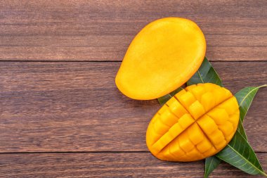 Taze mango-koyu ahşap ahşap arka planda yeşil yaprakları ile güzel doğranmış meyve. Tropikal meyve tasarım kavramı. Düz yatıyordu. Üst görünüm. Boşluk Kopyala