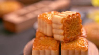 Siyah arduvaz arka planda çay ve çiçek ile ahşap bir tepsi üzerinde dönen güzel ay kek. Çin geleneksel Orta Sonbahar Festivali kavramı video.