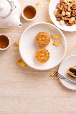 Güzel desen ile Sonbahar ortası festivali için lezzetli ay pastası, sarı çiçekler ve çay ile dekore edilmiştir. Şenlikli öğleden sonra pasta tasarımı kavramı