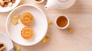 Güzel desen ile Sonbahar ortası festivali için lezzetli ay pastası, sarı çiçekler ve çay ile dekore edilmiştir. Şenlikli öğleden sonra pasta tasarımı kavramı