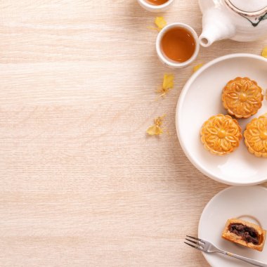 Güzel desen ile Sonbahar ortası festivali için lezzetli ay pastası, sarı çiçekler ve çay ile dekore edilmiştir. Şenlikli öğleden sonra pasta tasarımı kavramı