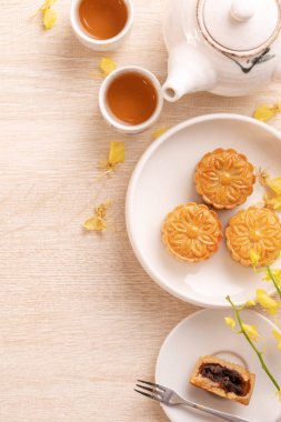 Güzel desen ile Sonbahar ortası festivali için lezzetli ay pastası, sarı çiçekler ve çay ile dekore edilmiştir. Şenlikli öğleden sonra pasta tasarımı kavramı