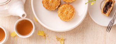 Güzel desen ile Sonbahar ortası festivali için lezzetli ay pastası, sarı çiçekler ve çay ile dekore edilmiştir. Şenlikli öğleden sonra pasta tasarımı kavramı