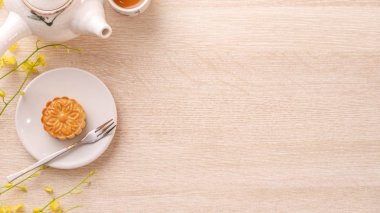 Güzel desen ile Sonbahar ortası festivali için lezzetli ay pastası, sarı çiçekler ve çay ile dekore edilmiştir. Şenlikli öğleden sonra pasta tasarımı kavramı