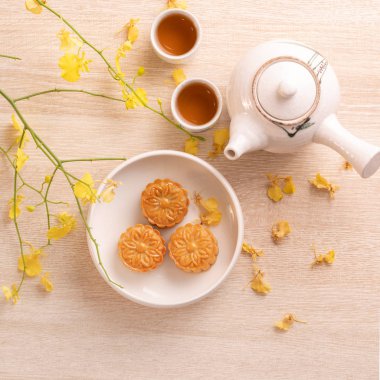 Güzel desen ile Sonbahar ortası festivali için lezzetli ay pastası, sarı çiçekler ve çay ile dekore edilmiştir. Şenlikli öğleden sonra pasta tasarımı kavramı