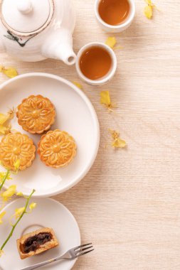 Güzel desen ile Sonbahar ortası festivali için lezzetli ay pastası, sarı çiçekler ve çay ile dekore edilmiştir. Şenlikli öğleden sonra pasta tasarımı kavramı