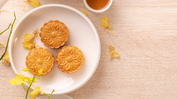 Delicious moon cake for Mid-Autumn festival with beautiful pattern, decorated with yellow flowers and tea. Concept of festive afternoon pastry design — Stock Photo, Image