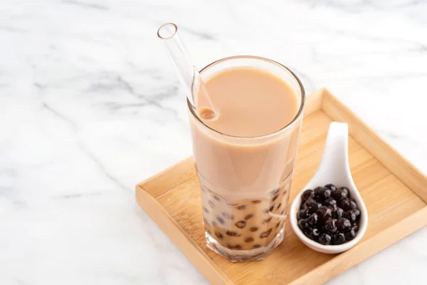 Tapioca inci topu kabarcık süt çayı, popüler Tayvan içecek, mermer beyaz masa ve ahşap tepsi üzerinde saman ile içme camı, yakın çekim, kopya alanı. — Stok fotoğraf