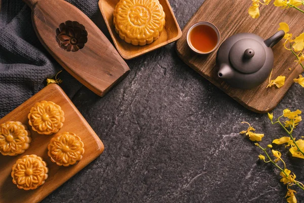 Mitten im Herbstfest traditionelles Essenskonzept - schöner Mondkuchen auf schwarzem Schiefertisch mit Tee, Gebäckform, Blume, Draufsicht, flache Lage, Kopierraum — Stockfoto