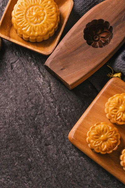 Mid-Autumn Festival traditional food concept - Beautiful Moon cake on black slate table with tea, pastry mold, flower, top view, flat lay, copy space