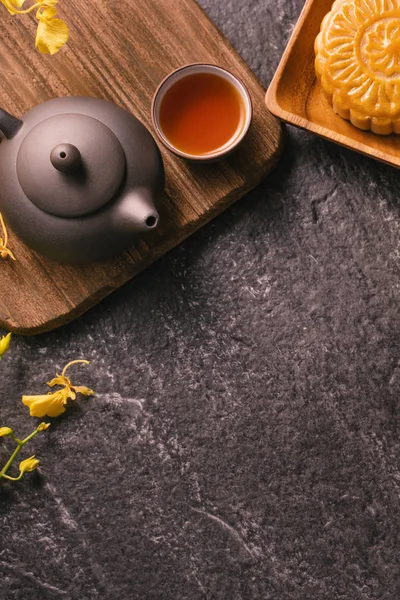 Mitten im Herbstfest traditionelles Essenskonzept - schöner Mondkuchen auf schwarzem Schiefertisch mit Tee, Gebäckform, Blume, Draufsicht, flache Lage, Kopierraum — Stockfoto