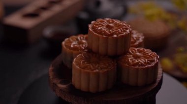 Siyah kayrak arka plan üzerinde çay ve çiçek ile ahşap bir tepsi üzerinde Güzel Moon kek. Çin geleneksel Orta Sonbahar Festivali kavramı, solmaya.