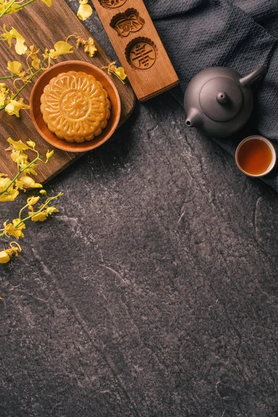 Mitten im Herbstfest traditionelles Essenskonzept - schöner Mondkuchen auf schwarzem Schiefertisch mit Tee, Gebäckform, Blume, Draufsicht, flache Lage, Kopierraum — Stockfoto