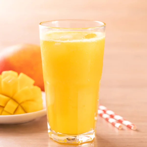 Свежий сок манго с красивой рубленой мякотью и соломой на ярком деревянном фоне стола. Концепция тропических фруктов. Закрыть, скопировать . — стоковое фото