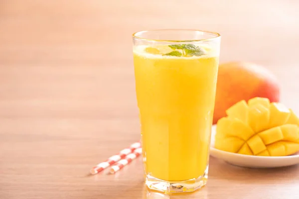 Fresh mango juice with beautiful chopped pulp flesh and straw on bright wooden table background. Tropical fruit design concept. Close up, copy space. — Stock Photo, Image