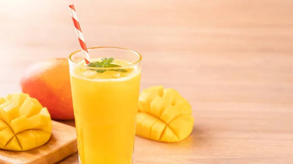 Fresh mango juice with beautiful chopped pulp flesh and straw on bright wooden table background. Tropical fruit design concept. Close up, copy space. — Stock Photo, Image