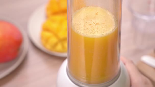 女人在明亮的木桌背景的夏季厨房制作新鲜的芒果汁 健康自制概念 — 图库视频影像