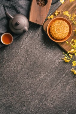 Mid-Autumn Festival traditional food concept - Beautiful Moon cake on black slate table with tea, pastry mold, flower, close up, copy space clipart