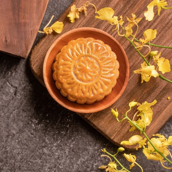 Mid-Autumn Festival traditional food concept - Beautiful Moon cake on black slate table with tea, pastry mold, flower, close up, copy space