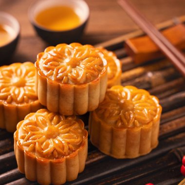 Orta Sonbahar Festivali için ahşap arka plan üzerinde bambu porsiyon uyarı tepsisi üzerinde çay bardak ile Çin geleneksel pasta Moon cake Mooncake, yakın.