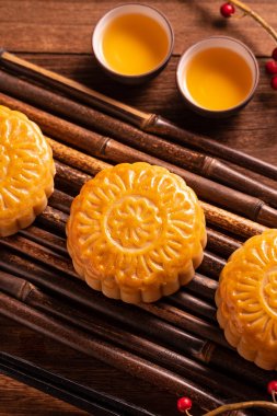 Orta Sonbahar Festivali için ahşap arka plan üzerinde bambu porsiyon uyarı tepsisi üzerinde çay bardak ile Çin geleneksel pasta Moon cake Mooncake, yakın.