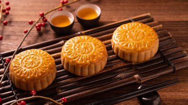 Orta Sonbahar Festivali için ahşap arka plan üzerinde bambu porsiyon uyarı tepsisi üzerinde çay bardak ile Çin geleneksel pasta Moon cake Mooncake, yakın.