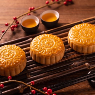 Orta Sonbahar Festivali için ahşap arka plan üzerinde bambu porsiyon uyarı tepsisi üzerinde çay bardak ile Çin geleneksel pasta Moon cake Mooncake, yakın.
