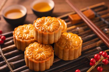 Orta Sonbahar Festivali için ahşap arka plan üzerinde bambu porsiyon uyarı tepsisi üzerinde çay bardak ile Çin geleneksel pasta Moon cake Mooncake, yakın.