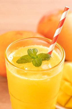 Parlak ahşap masa arka plan üzerinde güzel doğranmış hamuru eti ile taze mango suyu. Tropikal meyve içeceği tasarım konsepti. Kapat, kopyalama alanı.