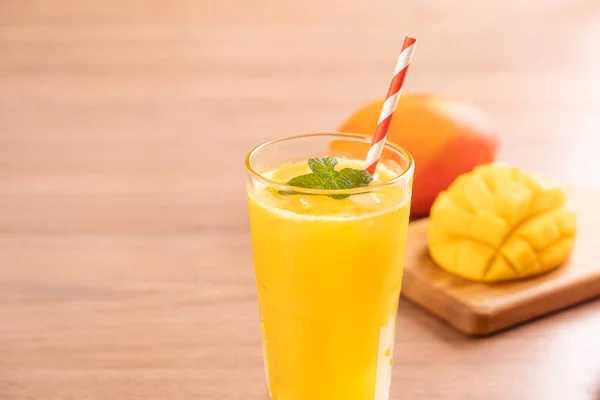 Sumo de manga fresco com bela polpa picada em fundo de mesa de madeira brilhante. Conceito de design de bebida de frutas tropicais. Fechar, espaço de cópia . — Fotografia de Stock