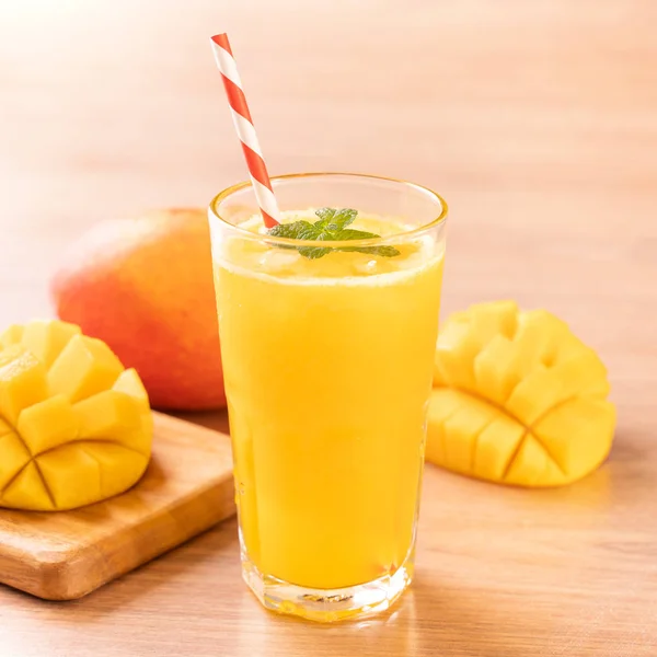 Fresh mango juice with beautiful chopped pulp flesh on bright wooden table background. Tropical fruit drink design concept. Close up, copy space. — Stock Photo, Image