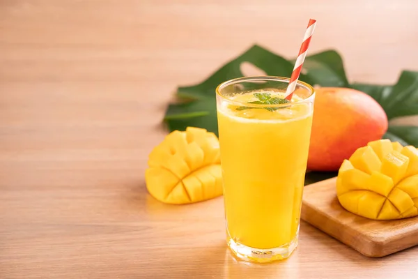 Свежий сок манго с красивой рубленой мякотью мякоти на ярком деревянном фоне стола. Концепция тропических фруктовых напитков. Закрыть, скопировать . — стоковое фото