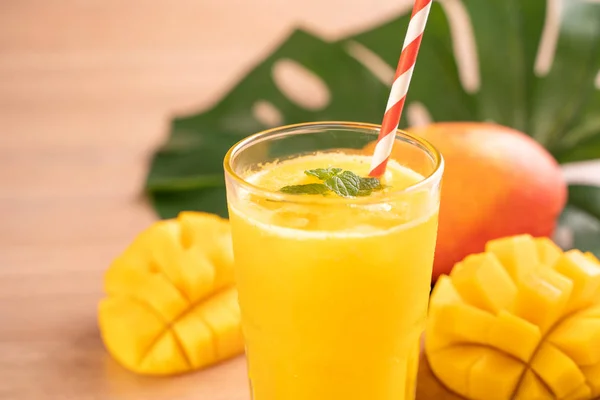 Fresh mango juice with beautiful chopped pulp flesh on bright wooden table background. Tropical fruit drink design concept. Close up, copy space. — Stock Photo, Image