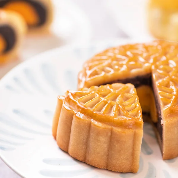 Festival de Medio Otoño concepto de comida tradicional - Hermosa torta de luna cortada en placa de patrón azul sobre fondo blanco con flor, primer plano, espacio de copia — Foto de Stock