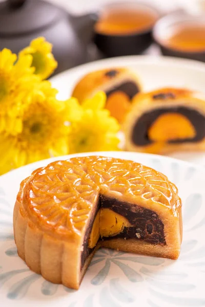 Conceito de comida tradicional do Festival do Meio do Outono - Bolo de lua cortado bonito na placa de padrão azul no fundo branco com flor, close-up, espaço de cópia — Fotografia de Stock