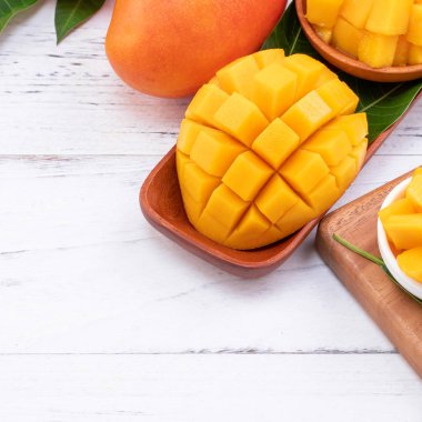 Bir tepsi ve parlak rustik ahşap arka planda taze doğranmış mango. Tropikal yaz meyve tasarım kavramı, yakın çekim, makro, kopya alanı.